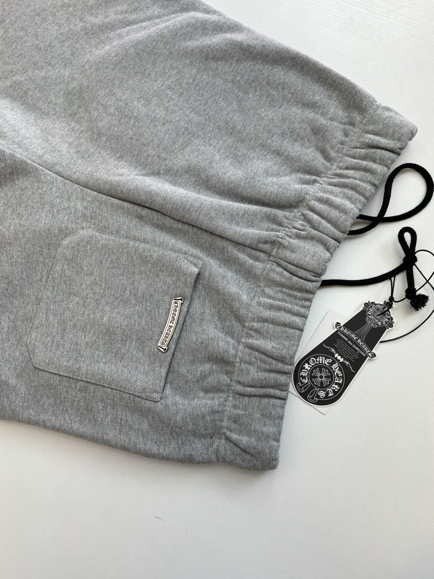 P346 Chrome Hearts*/Chrome Hearts 26SS early spring new patch embroidered shorts The fabric is made of a blended ratio of 80% cotton and 20% polyester. It is woven with a siro spinning process of 32-count base yarn and 10-count veil to form a high-weight terry cloth base of 380g/㎡. The cotton-polyester blended material combines the skin-friendly breathability of cotton and the anti-wrinkle shape retention of polyester. The high-weight fabric gives the trousers excellent stiffness and drape. The core technology is patch embroidery, which is completed with the help of TAJIMA computer embroidery machine. The black special-shaped patch is precisely sewn to the trouser fabric through lock stitches. The embroidery stitch density is even and the edges are neatly hemmed, forming a three-dimensional relief-like visual effect. Size: S/M/L/XL